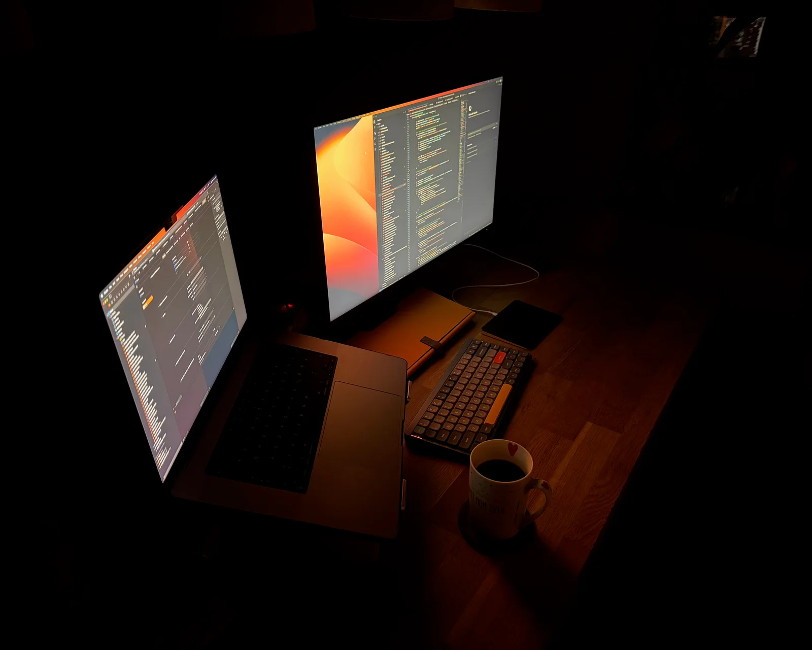 A dark late-night coding desk with two glowing screens and a coffee cup
